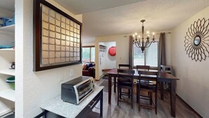 Uma sala de jantar com mesa e cadeiras, um candelabro e um espelho decorativo fixado na parede.