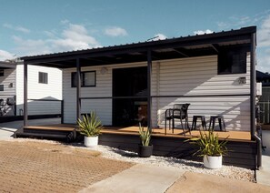 A mobile home with a covered porch, two potted plants, and a small table and chair set. - Clyde C - Family Cabin Sleeps 5 with Bunks (Mollymook)