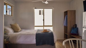 Une chambre à coucher comprenant un lit, un ventilateur de plafond, une fenêtre, une armoire et une chaise.