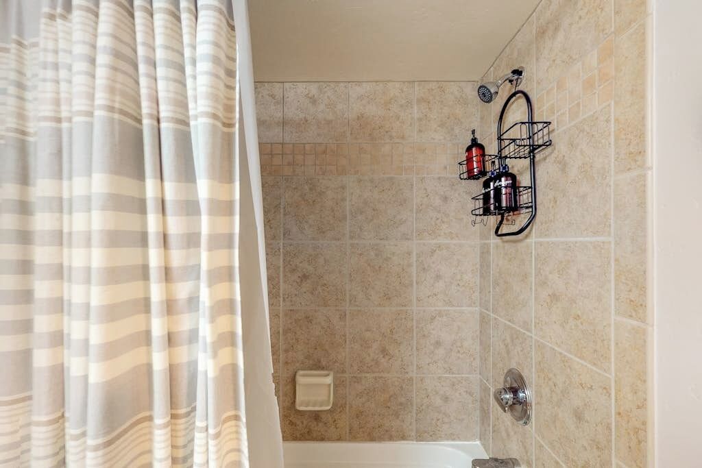 Een badkamer met een douche, een handdoekhouder en een zeepbakje.