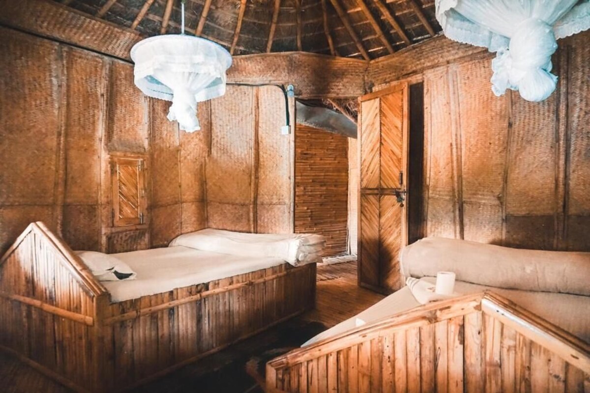 Una habitación rústica de madera con una cama, un sofá y una lámpara colgante.