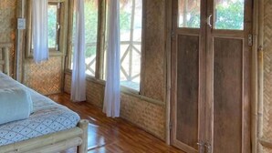 A room with a bed, wooden floor, large windows with curtains, and a wooden door. - Happy Lemon Tree Lodge (Sauraha)