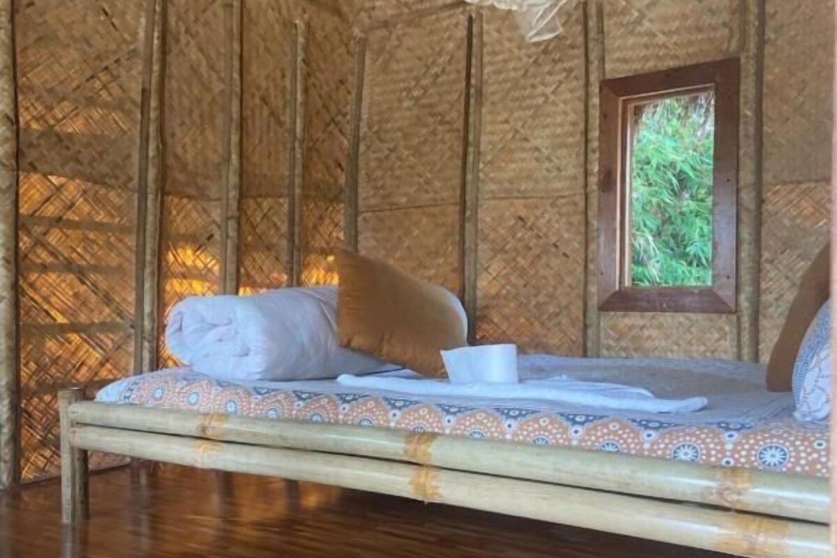 Una habitación con cama, ventana y techo de paja.