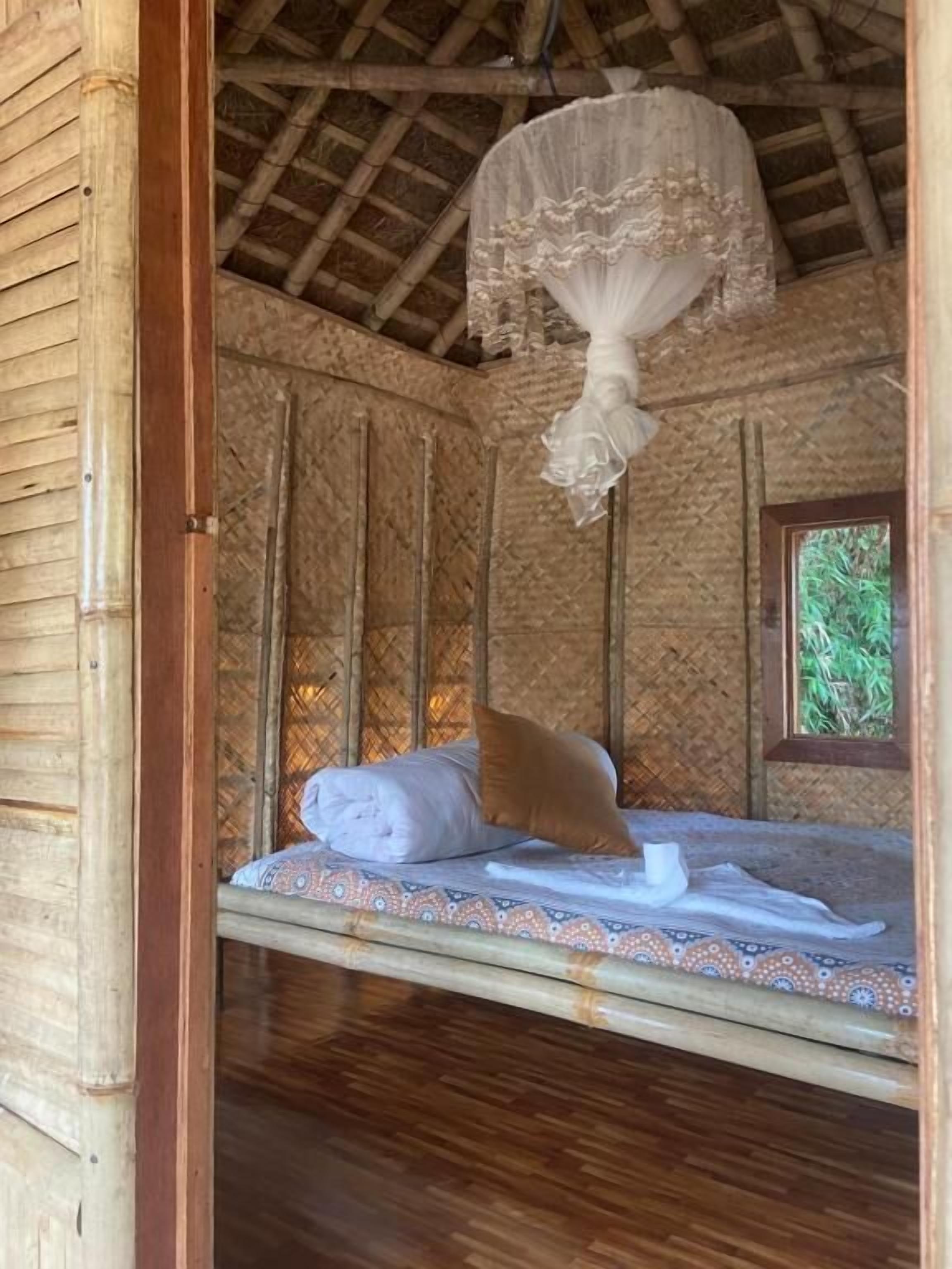 Una habitación con una cama, una ventana y una mosquitera colgante.