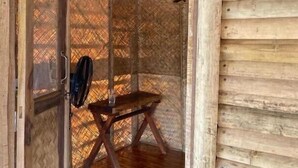A wooden cabin interior with a wooden floor, a table, and a chair. - Happy Lemon Tree Lodge (Sauraha)