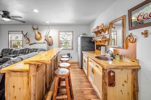 Eine Küche mit Holzhockern, einem Kühlschrank und Wandleuchtern aus Hirschgeweihen.