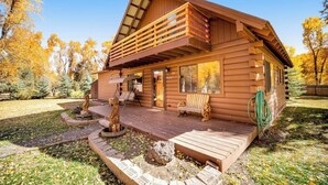 Une cabane en rondins dotée d’un balcon, d’une véranda et d’un foyer extérieur.