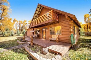 Eine Blockhütte mit Balkon, Veranda und Feuerstelle.