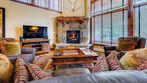 A cozy living room with a stone fireplace, leather sofas, and a mounted deer head. - 1442 EagleRidge Walk to the gondola Townhome w/ deck, fireplace, W/D & shared hot tubs/pool (Steamboat Springs)