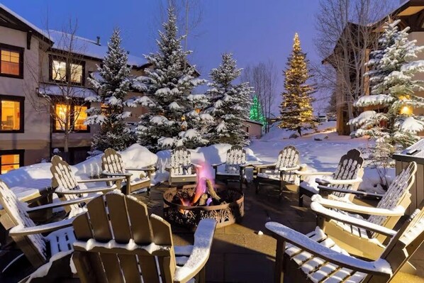 A snow-covered outdoor seating area with Adirondack chairs and a fire pit. - Walk to the gondola Townhome w/ deck, fireplace, W/D & shared hot tubs/pool (Steamboat Springs)