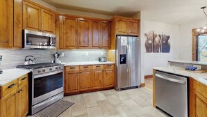 Una cocina con armarios de madera, electrodomésticos de acero inoxidable y suelo de baldosas.