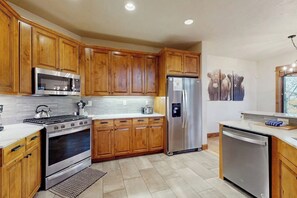 A kitchen with wooden cabinets, stainless steel appliances, and a tiled floor. - 1455 EagleRidge Luxury Townhome w/ Shared Pool and Hot Tub, Fitness Center, and Firepit (Steamboat Springs)