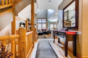 Eine Holztreppe führt zu einem Wohnbereich mit einer Couch, einem Couchtisch und einem Kamin.