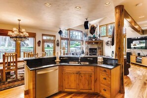Eine Küche mit einer großen Kochinsel, Holzschränken, einem Kamin und einem Essbereich mit Holzsesseln.