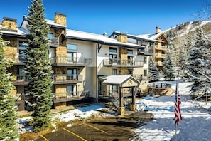 Ein mehrstöckiges Hotel mit Balkonen, einer überdachten Eingangsparte und verschneiter Landschaft.