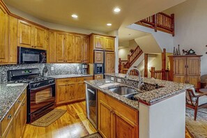 Eine Küche mit Holzschränken, Granitarbeitsplatten, einem Backofen, einer Mikrowelle, einem Spülbecken und einem Geschirrspüler.