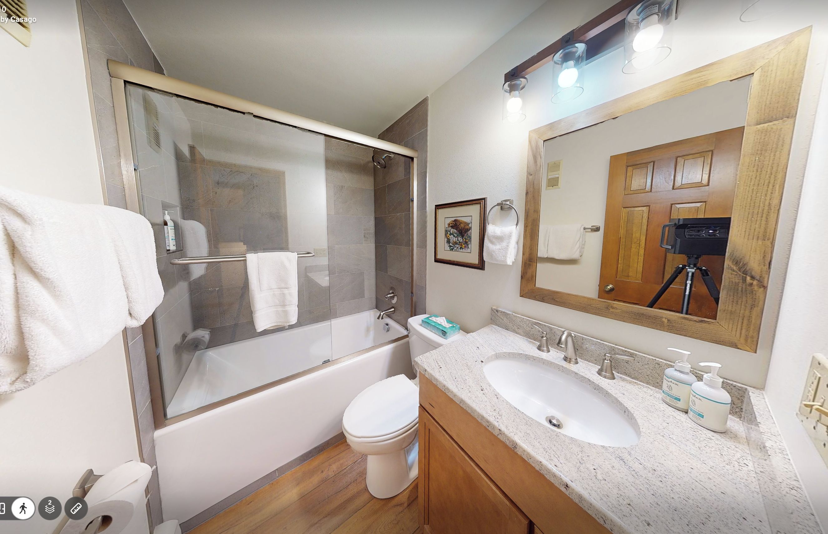 A modern bathroom with a glass-enclosed shower, a white toilet, a sink with a mirror, and a wooden vanity.
