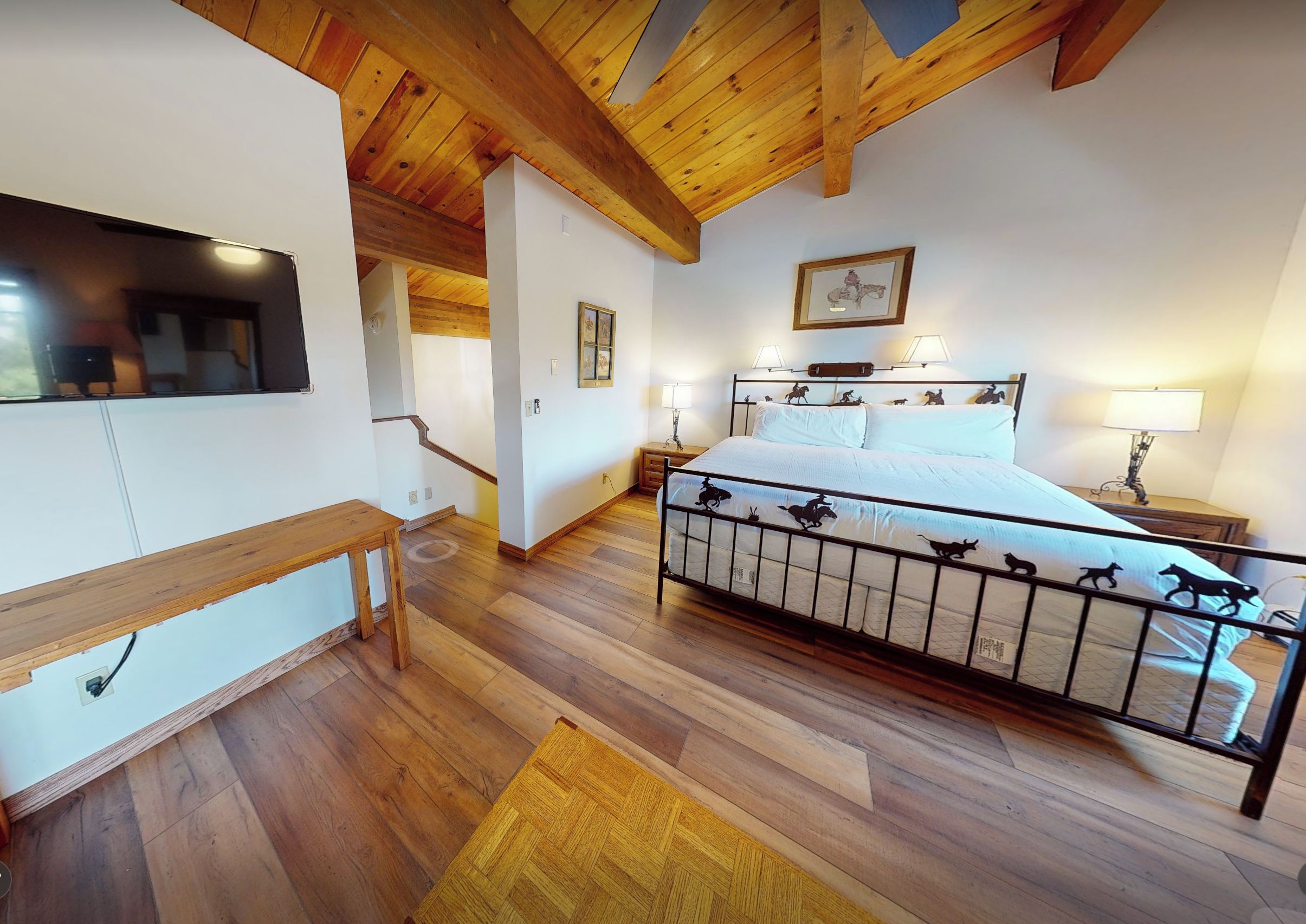 Ein Schlafzimmer mit Holzboden, einem Bett mit Metallgestell und einem Nachttisch mit Lampe.