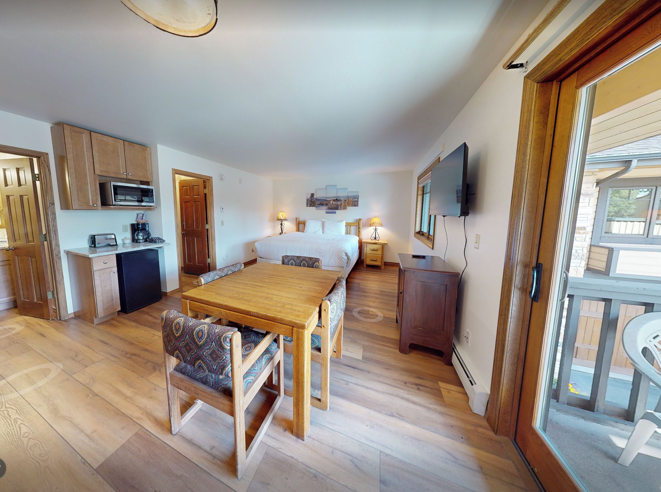 Ein kompakter Raum mit einer Küchenzeile, einem Essbereich, einem Bett und einem Fernseher.