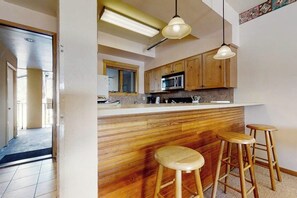 Eine Küche mit Holzausstattung, einer Mikrowelle und einer Bar mit Hockern.