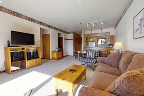 Ein Wohnzimmer mit einer Couch, einem Couchtisch, einem Fernseher und einer Holzkommode.