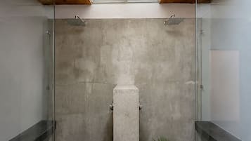 A modern shower area with a skylight, concrete walls, and a minimalist design.