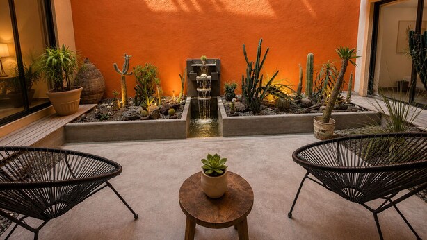 A courtyard with a water feature, potted plants, and two chairs.