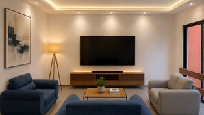 A modern living room with a large flat-screen TV, two sofas, a coffee table, and a floor lamp.
