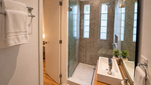 A modern bathroom with a glass-enclosed shower, a sink with a mirror, and a towel rack.