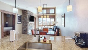 Una cocina moderna con encimeras de granito, un lavamanos de acero inoxidable y una cafetera.