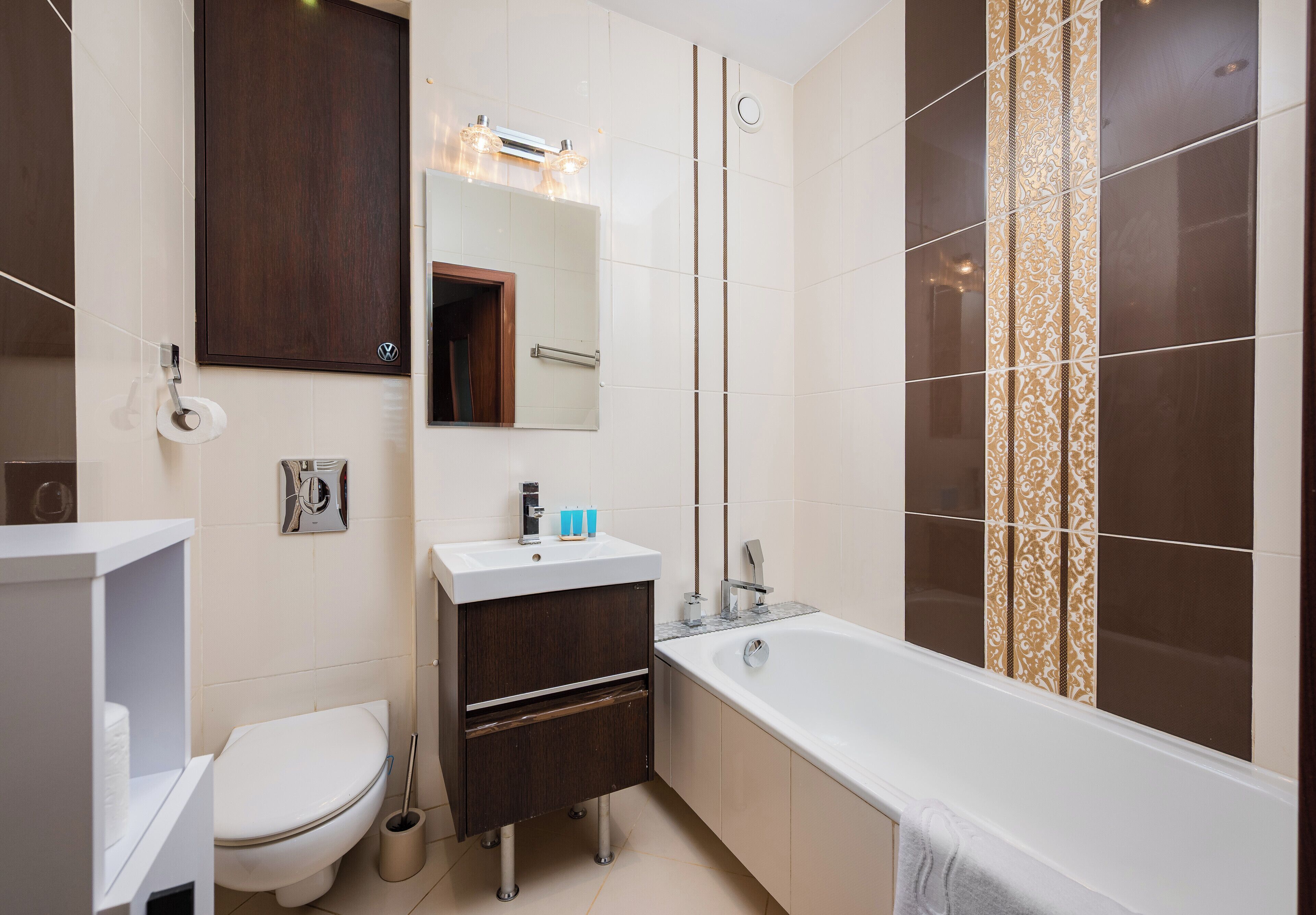 Et moderne badeværelse med toilet, vask, spejl og badekar.