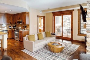 Eine moderne Küche mit Holzschränken, einer Mikrowelle und einem Essbereich mit einem weißen Sofa und Couchtisch.