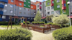 A multi-story residential building with balconies, a playground, and a fenced garden area. - Rutkiewicz City Comfort Apartment (Wrocław)