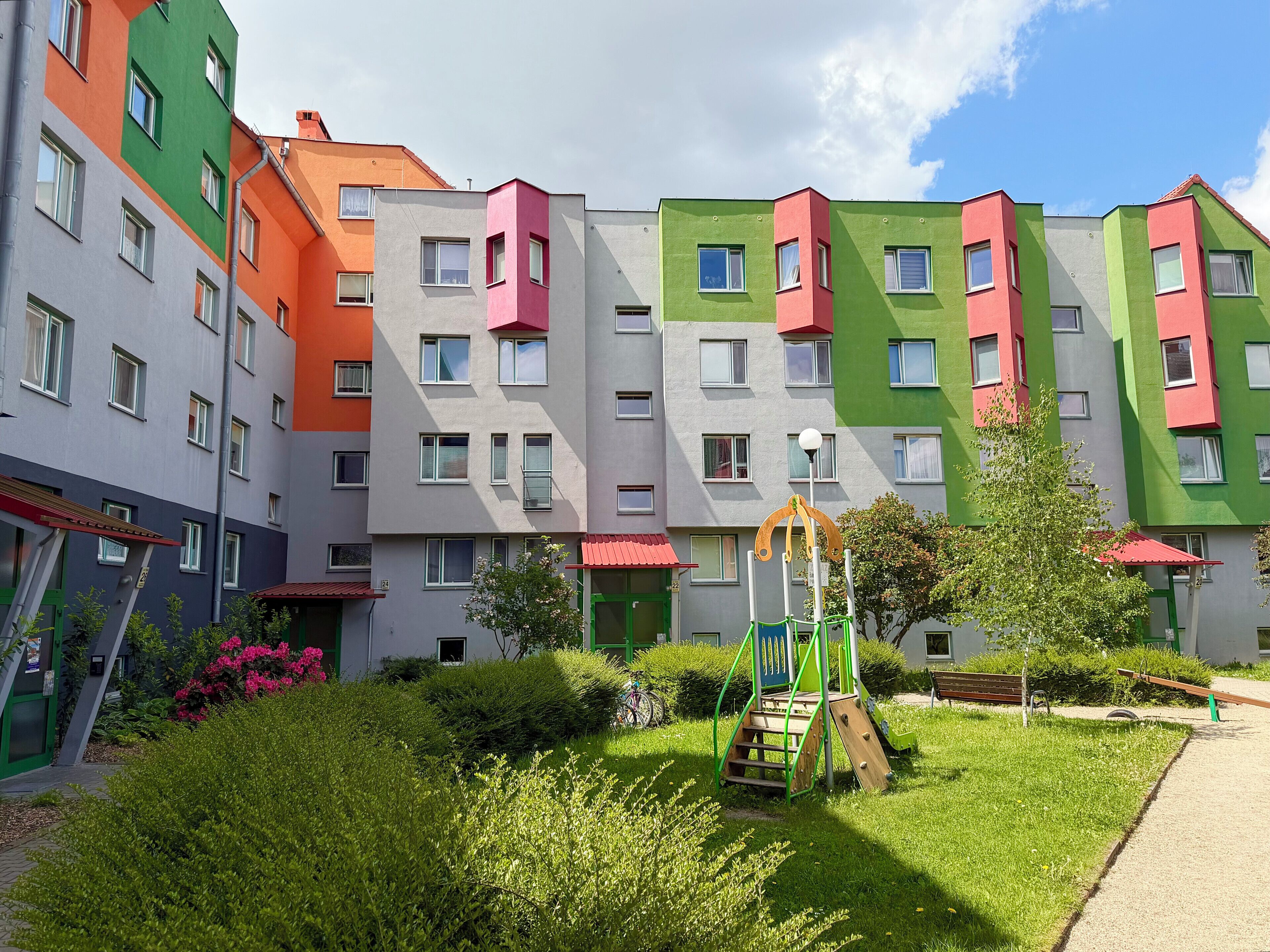 A multi-story residential building with balconies, a playground, and a well-maintained garden.