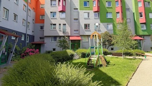 A multi-story residential building with balconies, a playground, and a well-maintained garden. - Rutkiewicz City Comfort Apartment (Wrocław)