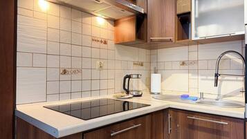 A modern kitchen with a black induction cooktop, wooden cabinets, and a stainless steel sink.