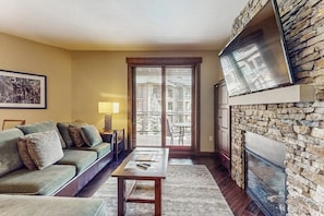 Ein Wohnzimmer mit einer Couch, einem Tisch, einem Kamin und einer Steinwand.