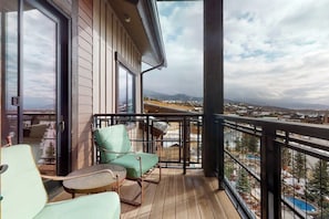 Ein Balkon mit Blick auf eine Berglandschaft, einem Holzboden und zwei grünen Stühlen.