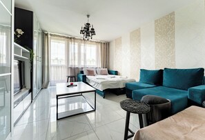 Ein modernes Wohnzimmer mit einer Couch, einem Couchtisch, einem Bett und einer Chandel.