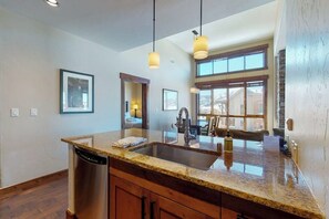 A kitchen with granite countertops, a dishwasher, pendant lights, and a large window. - Spacious & impressive condo w/view, gondola access & shared hot tubs, pool, gym (Steamboat Springs)