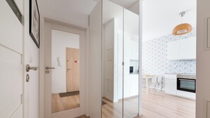 A modern kitchen with white cabinets, a wooden floor, and a hanging light fixture. - Kolska Chic Apartment (Warszawa)
