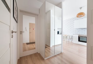 A modern kitchen with white cabinets, a wooden floor, and a hanging light fixture. - Kolska Chic Apartment (Warszawa)