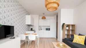 A modern living area with a dining table, sofa, TV, kitchen, and decorative wall. - Kolska Chic Apartment (Warszawa)