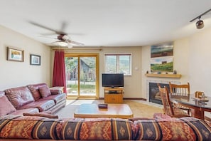 Ein Wohnzimmer mit einer Couch, Fernseher, Kamin und Deckenventilator.