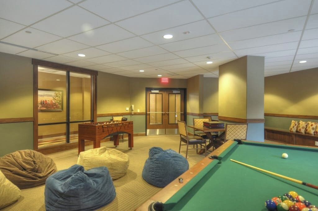 A pool table, bean bags, a chess table, and a door with an exit sign.