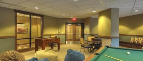 A pool table, bean bags, and a billiards table in a room with a traditional design.