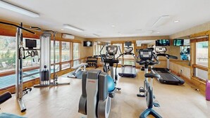 Un gimnasio con máquinas de cardio, equipo de pesas y amplias ventanas.