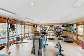 A gym with cardio machines, weight equipment, and large windows. - Lovely, modern getaway for the whole family w/ a shared pool & gym (Steamboat Springs)