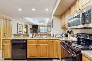 A kitchen with wooden cabinets, a dishwasher, a stove, and a microwave. - Lovely, modern getaway for the whole family w/ a shared pool & gym (Steamboat Springs)