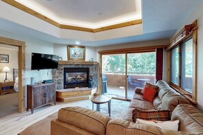 A living room with a fireplace, leather sofa, and a television. - Top-floor, corner condo w/ mountain views plus a shared pool & gym (Steamboat Springs)